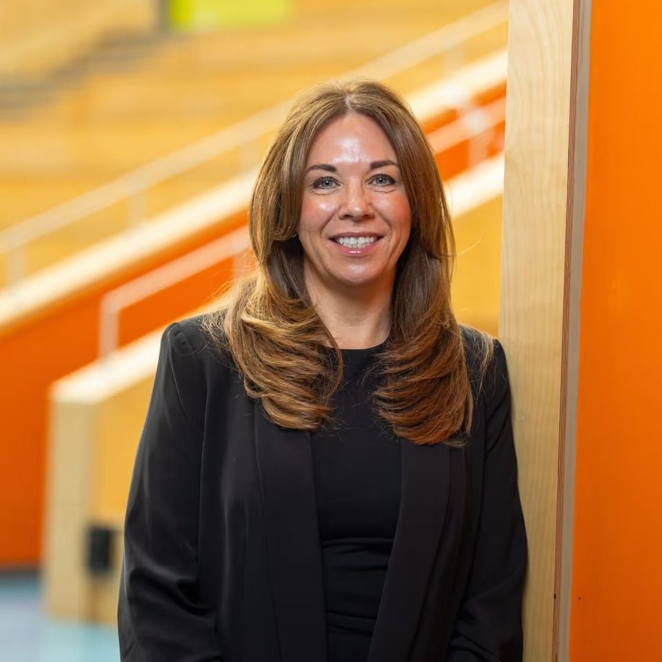 A person in a suit stands near a colorful stained glass window, looking contemplatively to the side.